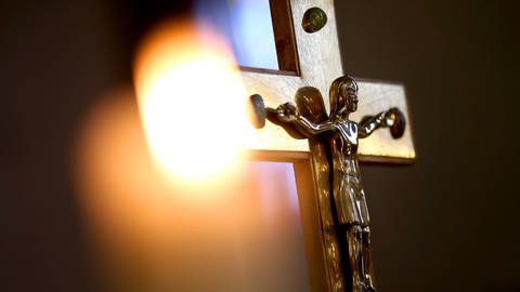 Ein Kreuz vor einer Kerze (Foto: dpa Bildfunk, picture alliance/dpa/dpa-Zentralbild | Ronny Hartmann)