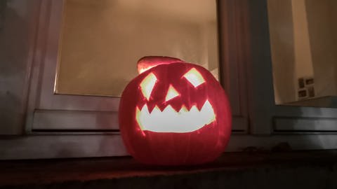 Kürbis in einem Fenster, nachts, mit ausgeschnittenem Gesicht, beleuchtet. Symbolbild Halloween. (Foto: SWR, Jürgen Härpfer)