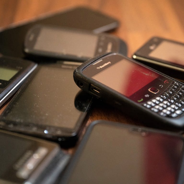 Ungenutzte Handys liegen auf dem Boden. Alte Elektrogeräte wie Rasierer oder Handys sollen Bürgerinnen und Bürger auch in Discountern und Supermärkten abgeben können.