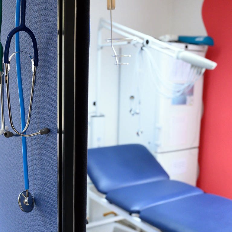 Stethoskope hängen im Behandlungszimmer einer Hausarztpraxis über einer Trennwand.