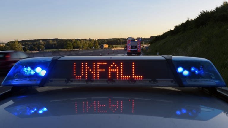 Auf einem Polizeifahrzeug warnt eine Leuchtschrift vor einer Unfallstelle