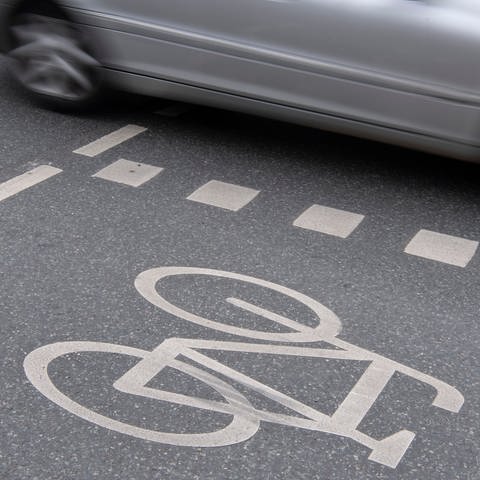 Ein Auto fährt neben einem Radweg (Symbolbild)