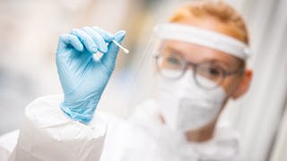 Eine Mitarbeiterin eines Testzentrums hält einen Teststab für einen Schnelltest auf das Coronavirus in ihren Händen (Foto: dpa Bildfunk, picture alliance/dpa | Moritz Frankenberg)