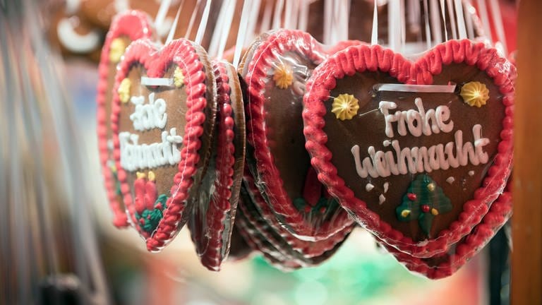 Lebkuchenherzen mit der Aufschrift "Frohe Weihnacht" hängen an einem Weihnachtsmarkt-Stand (Foto: dpa Bildfunk, Soeren Stache)
