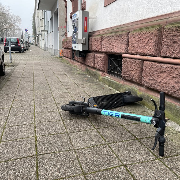 Ein E-Scooter liegt quer auf dem Gehweg