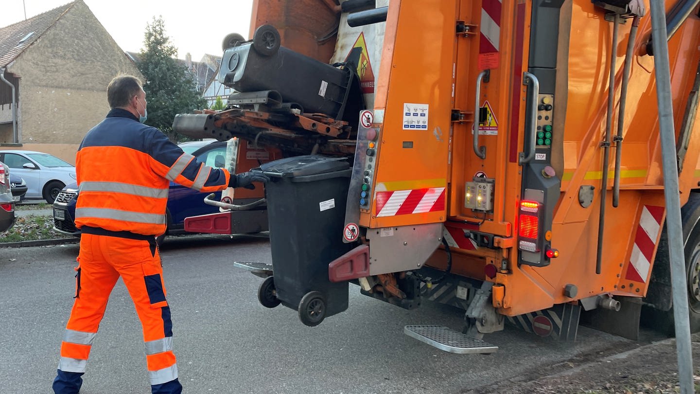 Rund 70 Mitarbeiter sind jeden Tag für Stadtreinigung und Müllabfuhr in Karlsruhe unterwegs. Müllmann hinter einem Müllauto bei der Arbeit. (Foto: SWR)