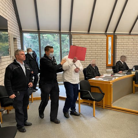 Angeklagter im Mädchenmordprozess wird in Baden-Baden von Polizisten in den Gerichtssaal geführt (Foto: SWR, Patrick Neumann)