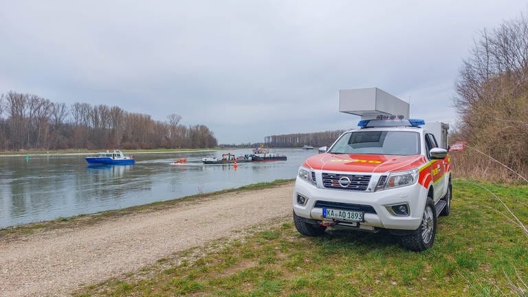 Ein DLRG-Fahrzeug am Rheinufer. Auf dem Fluss sind mehrere Rettungsboote (Foto: Pressestelle, Jan Bratzel - EinsatzReport24)