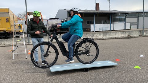 E-Bike-Fahrerin bekommt auf einem Parkplatz Fahrsicherheitstraining: Sie muss einen Parcours fahren. (Foto: SWR, Heiner Kunold)