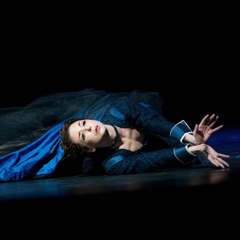 Eine Tänzerin liegt in bauem Kleid auf dem Bühenboden (Foto: Pressestelle, Yan Revazov (Badisches Staatstheater Karlsruhe))