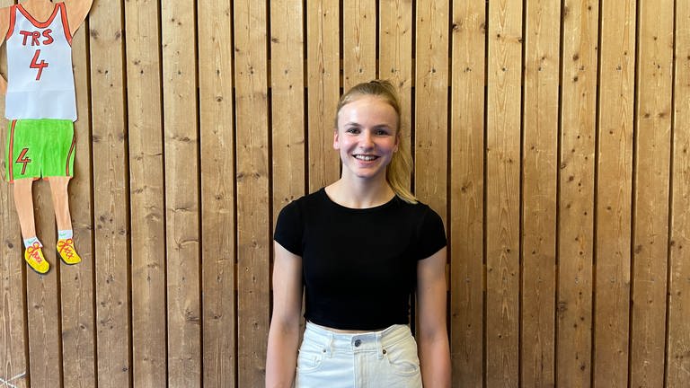 Anna-Lena König, Schülerin der Tulla-Realschule in Karlsruhe, steht in der Sporthalle vor einer hölzernen Wand. (Foto: SWR, Greta Hirsch)