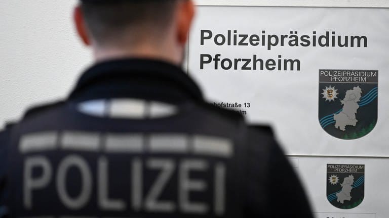 Polizist in Uniform steht mit dem Rücken zum Betrachter neben einem Schild mit der Aufschrift "Polizeipräsidium Pforzheim" (Foto: dpa Bildfunk, dpa / Uli Deck)