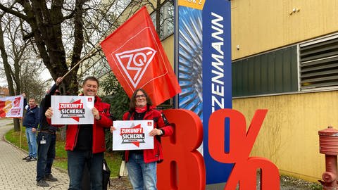 Zwei Streikende bei Witzenmann mit Schildern mit der Aufschrift "Zikunft sichern". Hinter ihnen steht eine fast mannshohe, rote 8 und ein Prozentzeichen. (Foto: SWR, Peter Lauber)