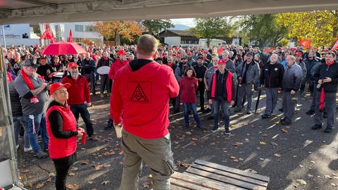 Ein Gewerkschafter in rotem IG-Metall-T-Shirt steht auf einer Pallette und spricht zu den Streikeden bei Schaeffler in Bühl (Foto: SWR, Patrick Neumann)