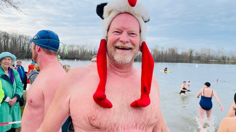 Neujahrsschwimmer am Baggersee in Grötzingen. Der bärtige Mann hat einen Plüsch-Storch als Kappe auf dem Kopf (Foto: SWR)