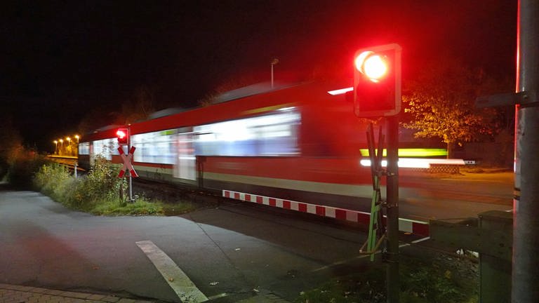 Zug überquert bei Dunkelheit einen geschlossenen Bahnübergang (Foto: Pressestelle, Deutsche Bahn)