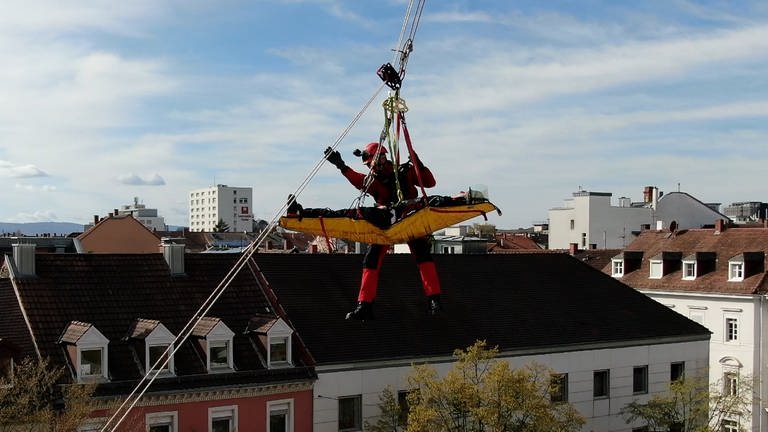 Bei einer Übung der Höhenrettungsgruppe Karlsruhe wird ein Kranfahrer abgeseilt. (Foto: SWR)