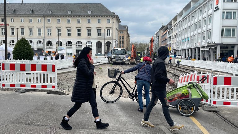 In der Kaiserstraße in der Karlsruher Innenstadt werden der Straßenbelag und alte Schienen rausgerissen, Fußgänger laufen an der Baustelle vorbei (Foto: SWR, Mathilde Weindel)