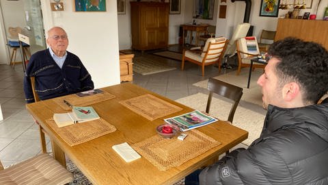 Der ehemalige syrische Flüchtling sowie Bürgermeisterkandidat Ryyan Alshebl ist in Ostelsheim auf Wahlkampftour. Er sitzt mit einem älteren Herren an einem Tisch. (Foto: SWR)