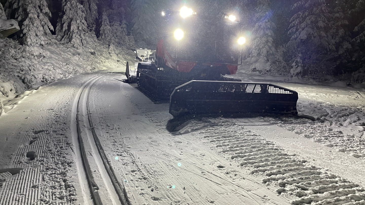 Nachts werden die Loipen an der Schwarzwaldhochstraße gespurt. Pistenbulli fährt im Dunkeln durch schneebedeckte Bäume. (Foto: SWR)