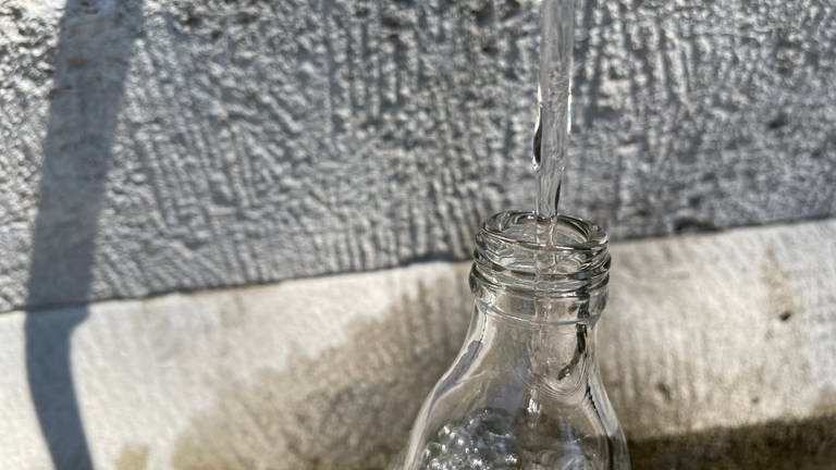Eine Flasche wird an einem Trinkwasserbrunnen aufgefüllt