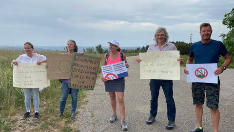 Windkraftgegner protestieren auf der Hornisgrinde. Sie halten Protestplakate vor sich.