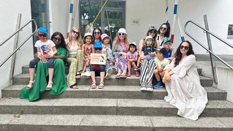 Kinder und Erzieherinnen der Kita "Mikado" in Karlsruhe halten die Auszeichnung für die Anwendung eines Sonnenschutzkonzeptes hoch. (Foto: Kita Mikado/Kerstin Saatzer)