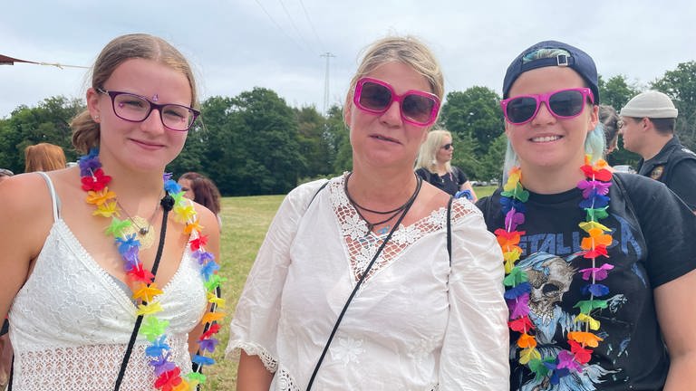 Drei Besucherinnen des Happiness-Festivals in Straubenhardt tragen pinke Sonnenbrillen und bunte Blumenketten (Foto: SWR, Mirka Tiede)