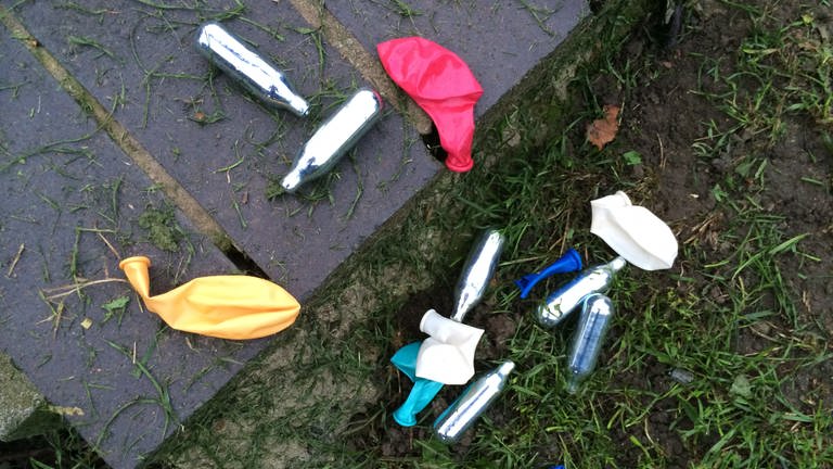 Lachgaskartuschen liegen neben Luftballons auf dem Boden. Immer häufiger konsumieren Jugendliche in Karlsruhe Lachgas, um sich zu berauschen. Doch die Droge birgt viele Gefahren.