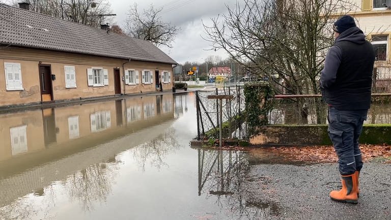 Sven Müller blickt auf ein Haus in Rastatt, das von Wasser eingekesselt ist. Das Hochwasser im Rhein hat teilweise den Stadtteil Plittersdorf überschwemmt. (Foto: SWR, Markus Bender)