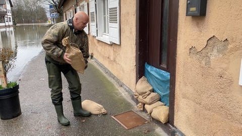 Maik Stattelberger sichert in Rastatt seine Haustür mit Sandsäcken. Er war auf das Hochwasser im Rhein vorbereitet. 