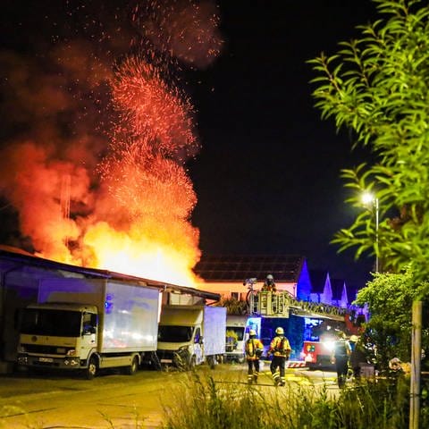 Hohe Flammen schlagen aus der Lagerhalle eines Möbelgeschäfts. Die Feuerwehr steht daneben und löscht den Brand im Kreis Karlsruhe.