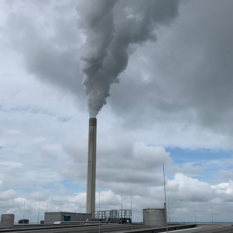 Das Kohlekraftwerk in Karlsruhe am Rhein von außen mit einem rauchenden Schornstein 