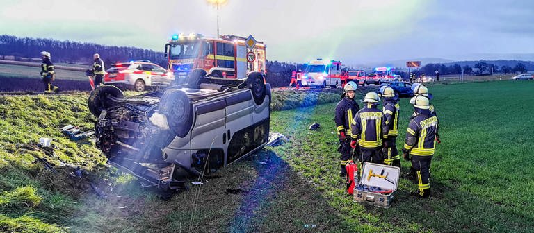 Feuerwehrleute stehen an einer Unfallstelle im Rhein-Neckar-Kreis neben einem schwer beschädigten Fahrzeug.  (Foto: dpa Bildfunk, Picture Alliance)