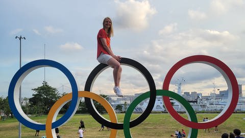 Die Leichtathletin Jessica-Bianca Wessolly sitzt in Tokio auf einer Skulptur mit den fünf olympischen Ringen (Foto: Privat)