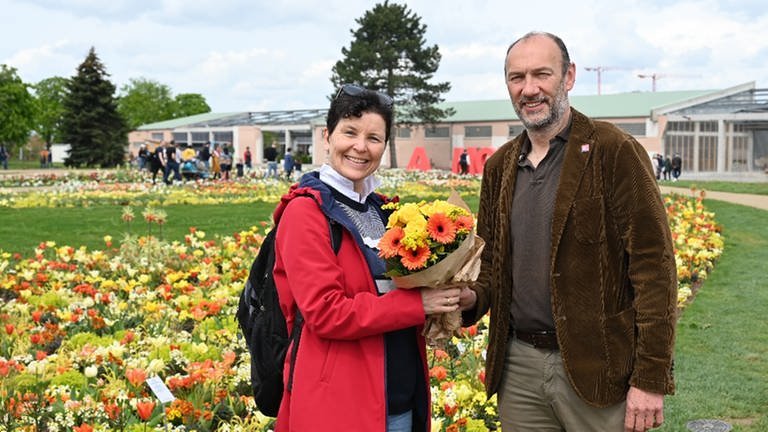 Die hunderttausendste BUGA-Besucherin Martina Büschert wurde von BUGA 23-Geschäftsführer Michael Schnellbach auf dem Spinelli-Gelände in Mannheim mit einem Blumenstrauß empfangen. (Foto: BUGA 23)