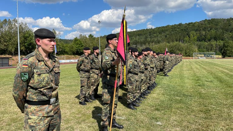 Ein Soldat desPanzerbatallion 363 Hardheim hält eine Fahne, neben ihm Kameraden: Etwa 300 Soldatinnen und Soldaten werden zu ihrem Einsatz nach Litauen verabschiedet.  (Foto: SWR, SWR/ Thomas Miltner)