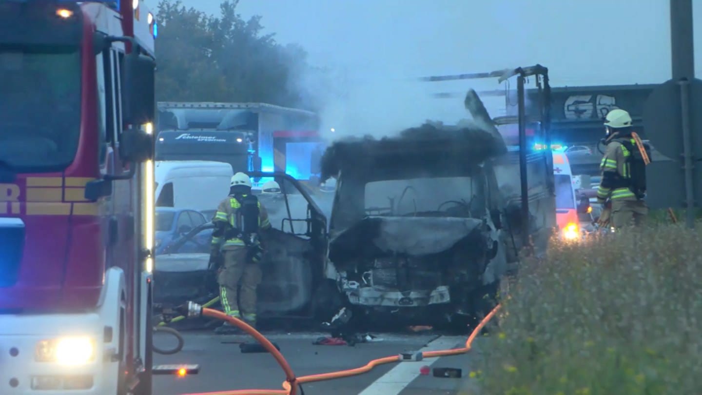Zwei Feuerwehrleute löschen einen brennenden Transporter nach einem Unfall auf der A5 bei Heidelberg. (Foto: TNN - die Video-Unit der dpa)