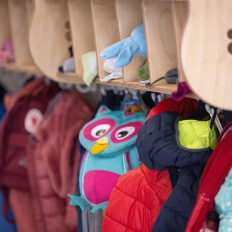 An einer Garderobe in einer Kita hängen Jacken und Kinderrucksäcke. (Foto: dpa Bildfunk, picture alliance/dpa | Marijan Murat)