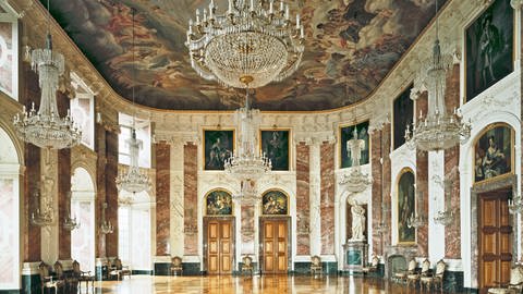 Der prunkvolle Rittersaal des Mannheimer Schlosses mit einer Wandmalerei an der Decke, Kronleuchtern und weiteren Malereien.