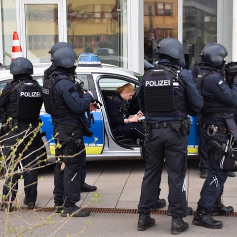 Schwer bewaffnete Polizisten und ein Streifenwagen stehen vor dem Bürogebäude. (Foto: René Priebe/PR-Video )