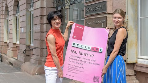 Bürgermeisterin Stefanie Jansen (l.) in Heidelberg und Gleichstellungsbeauftragte Dr. Marie-Luise Löffler mit dem Plakat zur Kampagne "perioHDe". (Foto: Pressestelle, Stadt Heidelberg/Rothe)