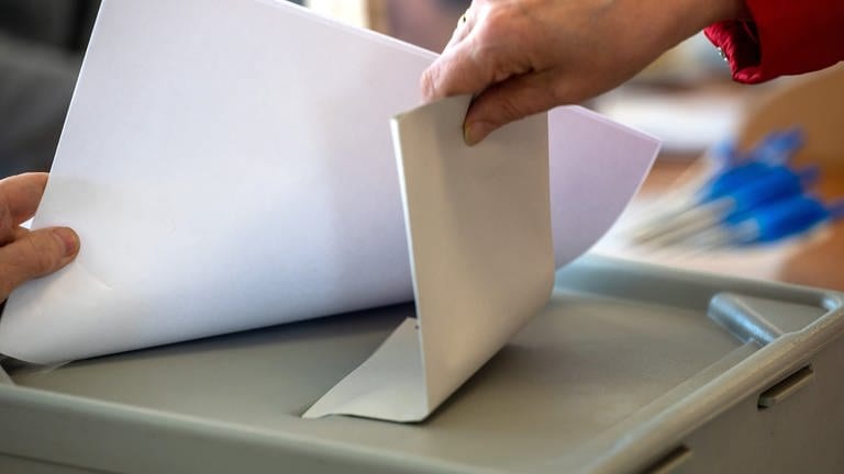 Frau steckt Wahlzettel in Urne