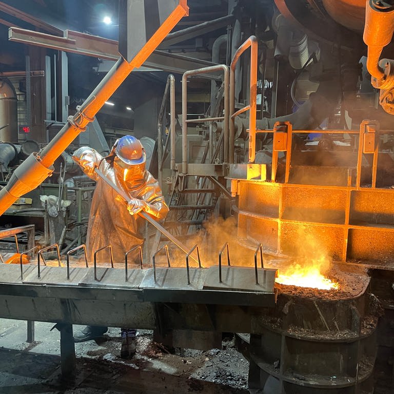 Mann in Schutzanzug an Anlage, in der flüssiges Eisen bearbeitet wird (Foto: SWR)