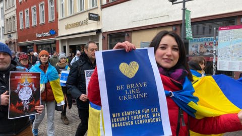 Eine Frau hält ein Plakat in die Höhe. Darauf steht: "Wir kämpfen für die Zukunft der Ukraine. Wir brauchen Leoparden 2".   (Foto: SWR)