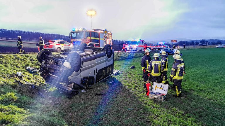 Feuerwehrleute stehen an einer Unfallstelle im Rhein-Neckar-Kreis neben einem schwer beschädigten Fahrzeug.  (Foto: dpa Bildfunk, Picture Alliance)