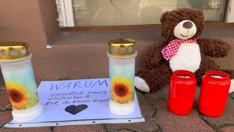 Kerzen und Kuscheltiere auf Bürgersteig in Hockenheim und ein Baltt mit der Frage "warum?" (Foto: SWR)