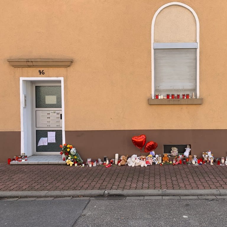 Kerzen, Kuscheltiere und Blumen auf Bürgersteig vor Wohnhaus in Hockenheim