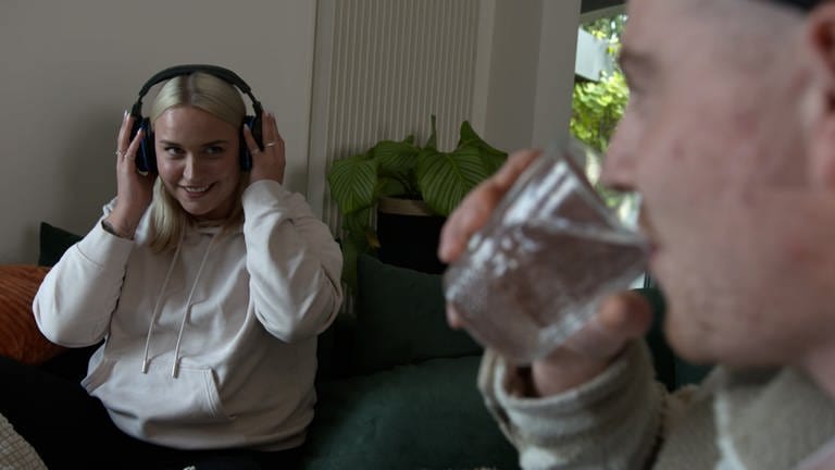 Theresas Freund trinkt, während sie Kopfhörer trägt und somit das Geräusch besser ertragen kann. (Foto: SWR, Theresa leidet an Misophonie)