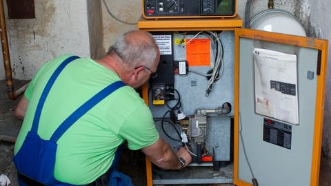 Ein Heizungsmonteur kontrolliert eine ältere Heizungsanlage: Ist sie optimal eingestellt, hilft das beim Sparen von Gas.